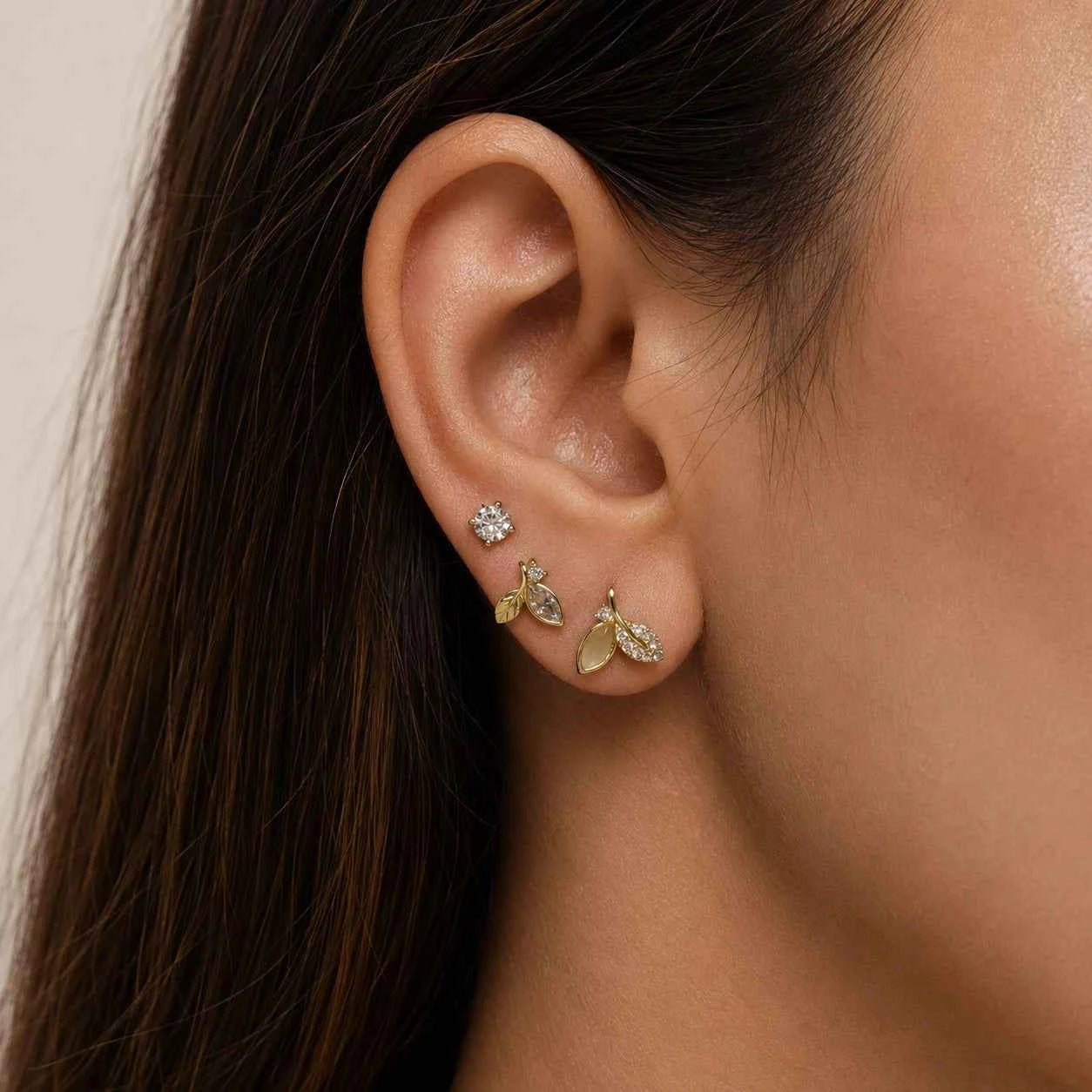 Gold-tone leaf crystal ear studs with small dangling charms on one side