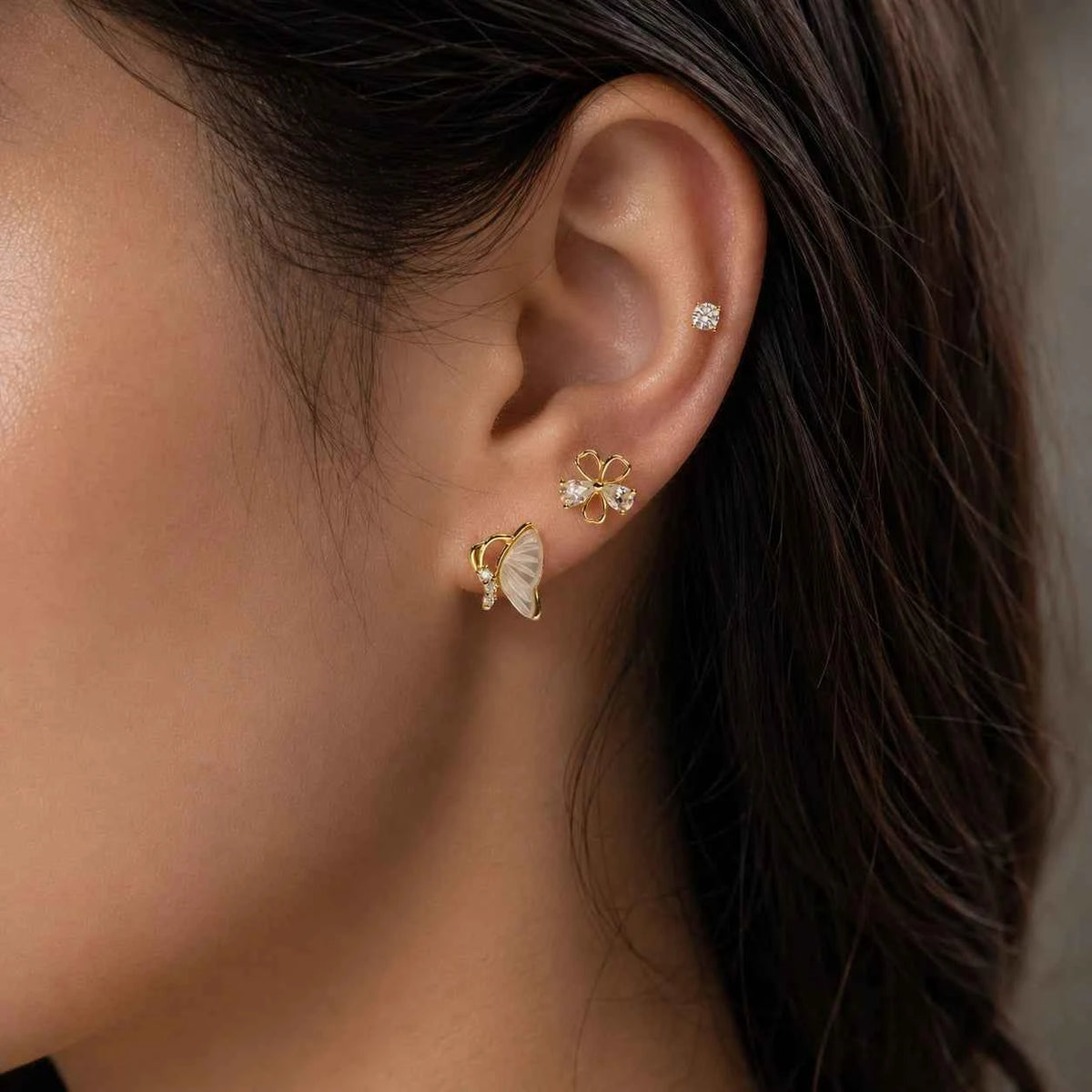 Gold floral and butterfly stud earrings with small crystal accents.