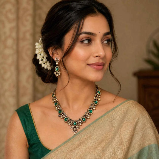 Gold-tone necklace with green oval stones and matching floral drop earrings, on model