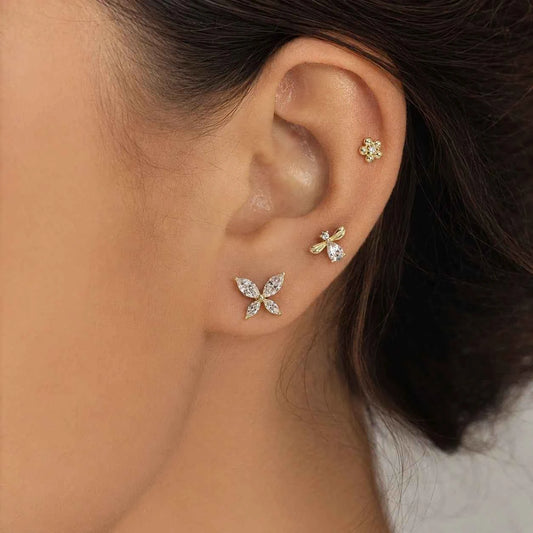 Gold-tone butterfly and floral cluster stud earrings on ear