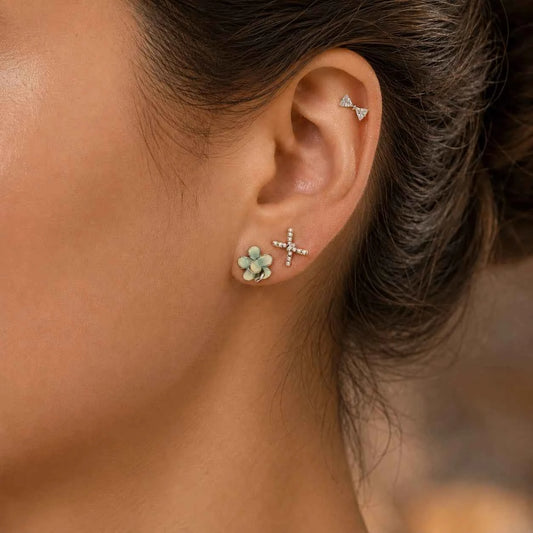 Silver-tone CZ cross and four-leaf flower stud earrings on ear