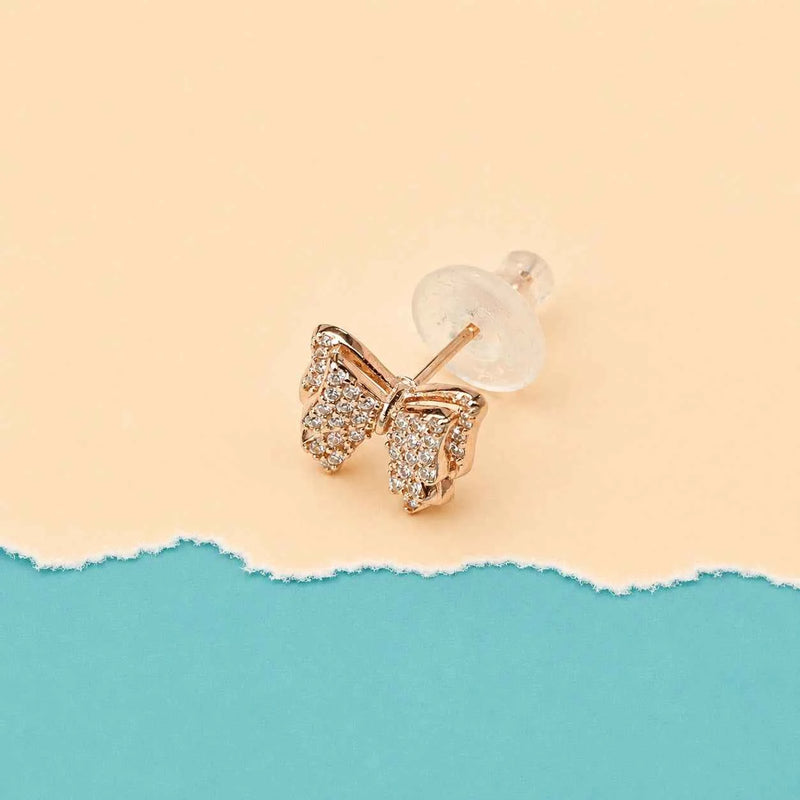 Rose gold bow stud earrings with crystal pavé and a visible secure stud back.