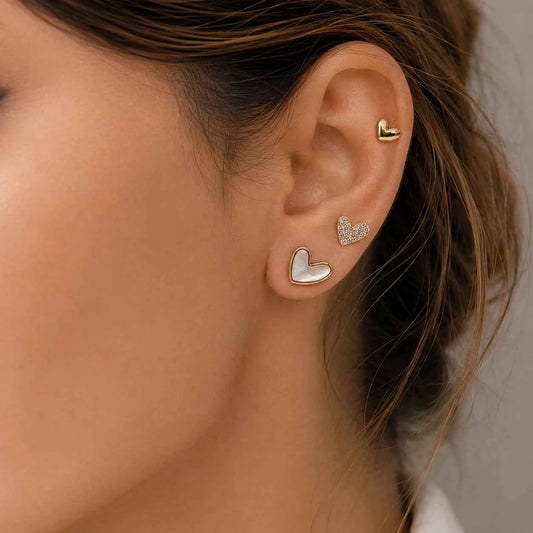 Gold-tone heart stud earrings on ear, small shiny and textured heart designs