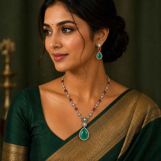 Drop pendant necklace with matching earrings on model, green teardrop center and red stones
