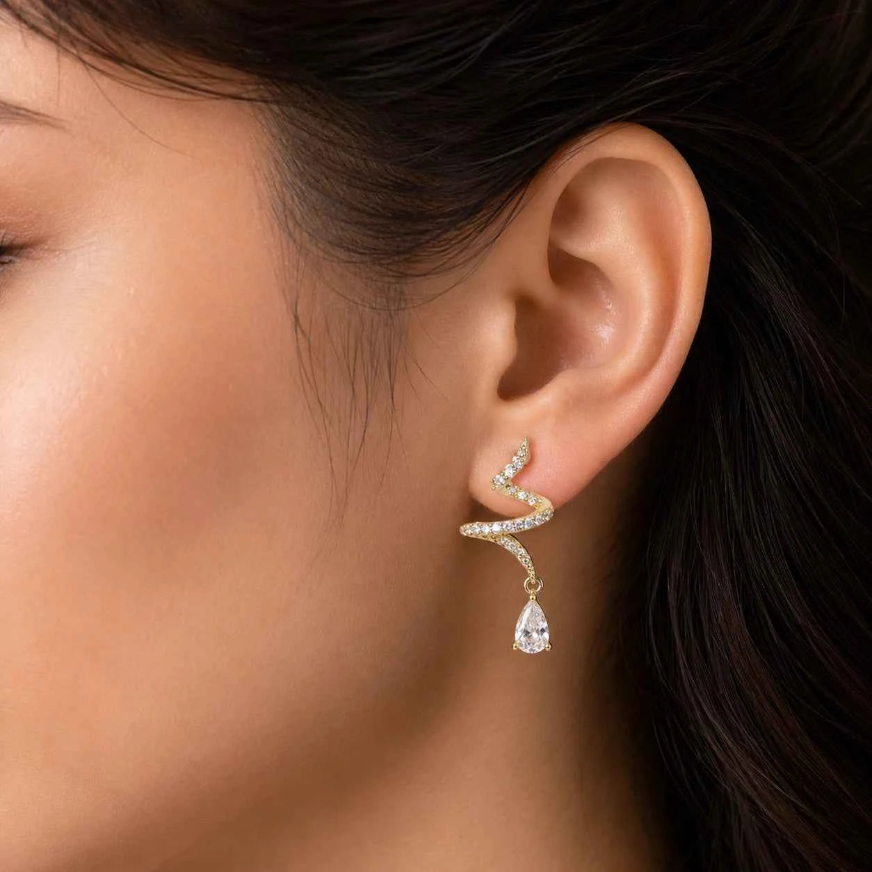 Gold-tone crystal drop earrings with zigzag swirl top and dangling teardrop stone