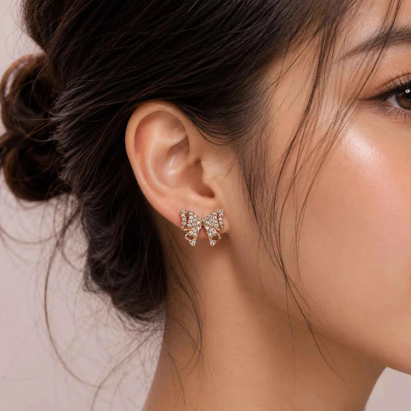 Rose gold bow stud earrings on an ear, butterfly bow with sparkling crystal pavé.