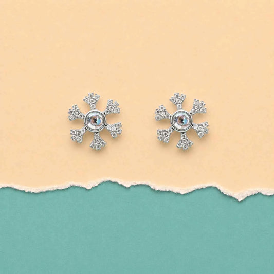 Two silver snowflake stud earrings with circular center and glittering pave details