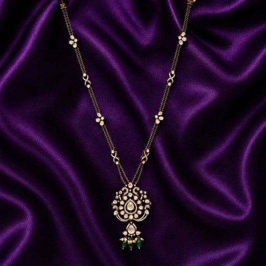 Gold-tone long chain pendant necklace with ornate circular centerpiece and green tassel