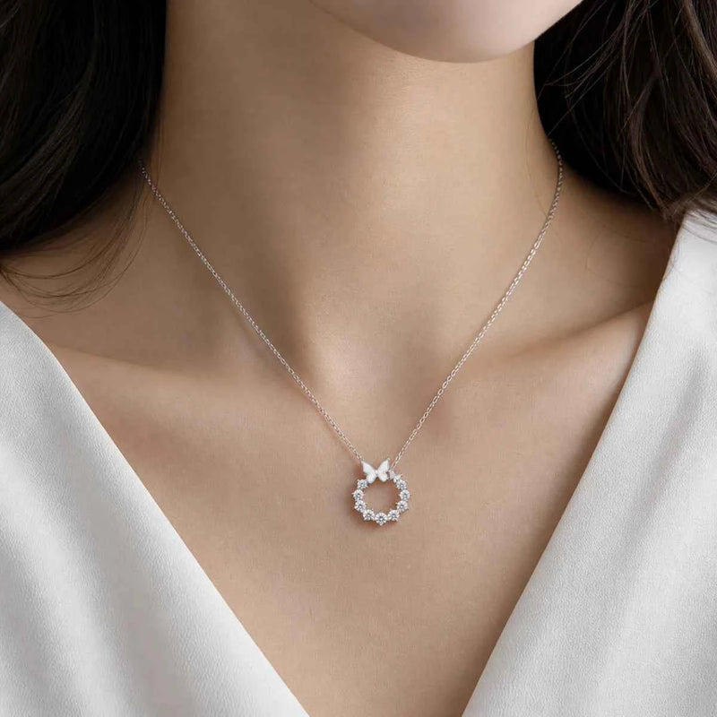 Silver butterfly halo necklace worn at neckline with small round halo pendant