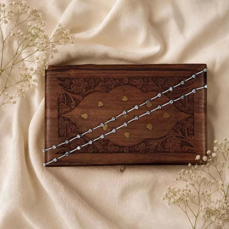 Silver beaded bracelet across wooden box on light fabric
