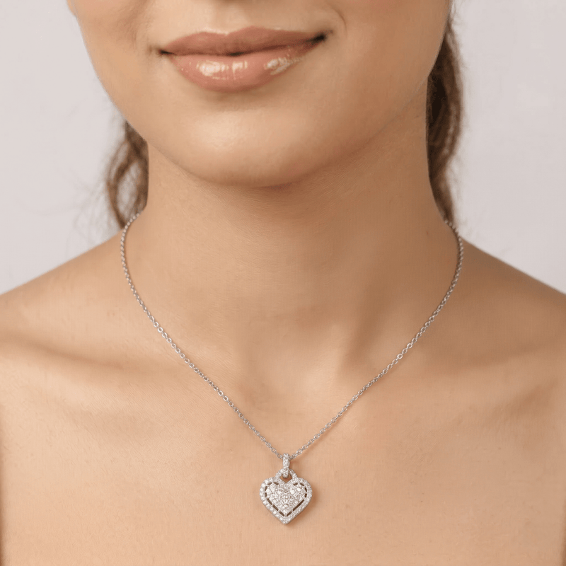 Silver heart sparkle pendant on short chain necklace, worn at neckline.