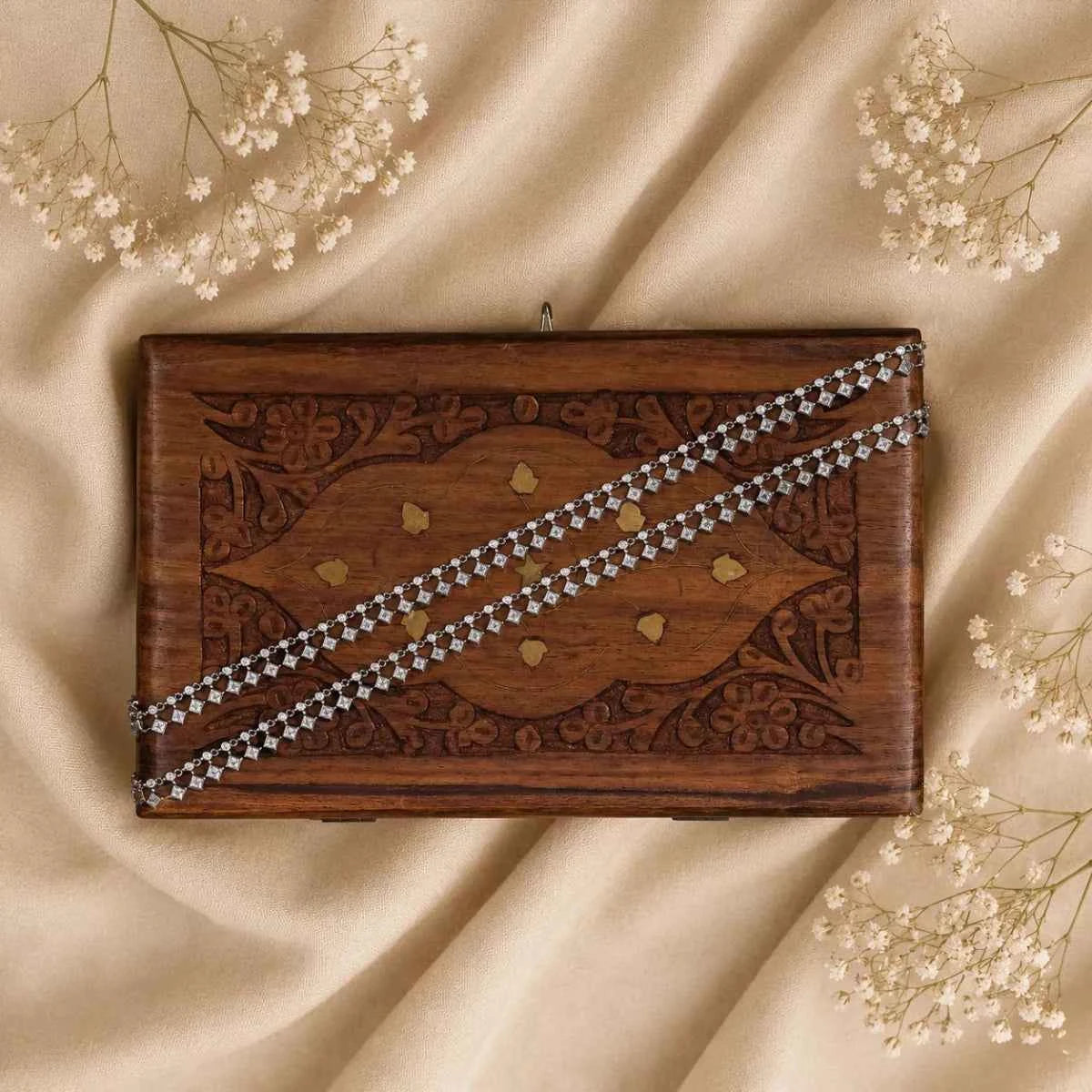 Silver crystal bracelet laid across a wooden board with small dangling charms
