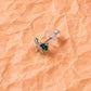 Silver bow charm stud earrings with emerald green gemstone centers, on posts.