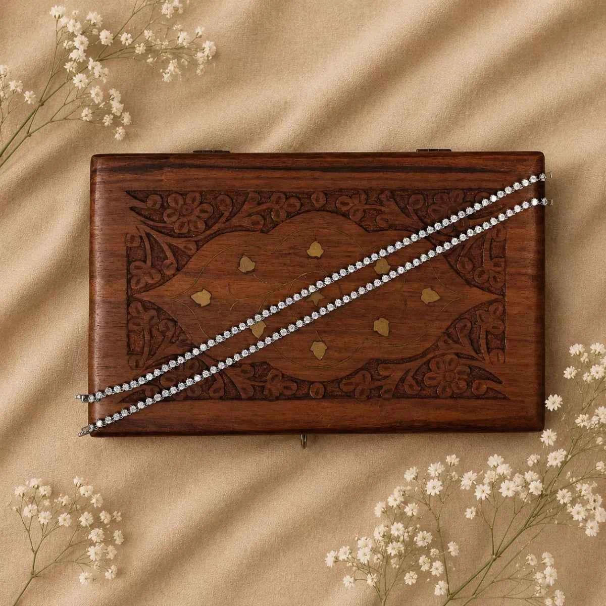 Silver 925 anklet pair with sparkling chain on wooden jewelry tray