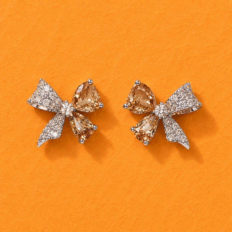 Pair of bow-shaped crystal stud earrings with clear stones in rose-gold tone