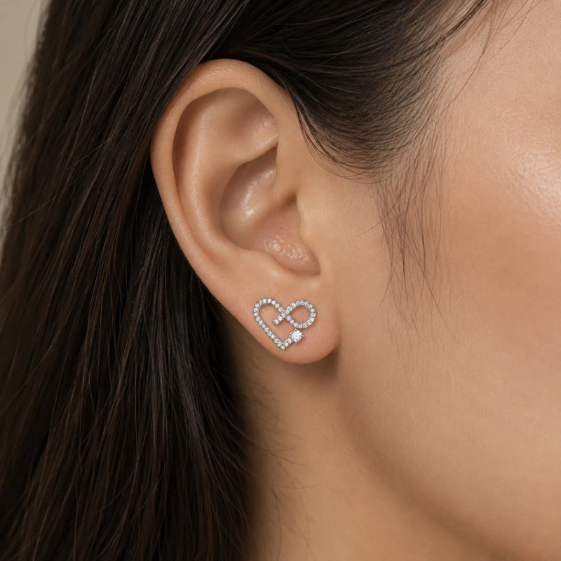 Infinity heart crystal stud earrings on ear, silver-tone with small pavé hearts