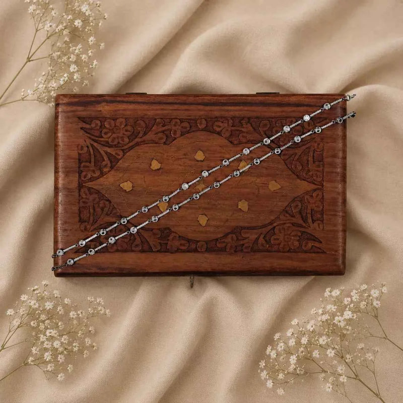 925 silver chain anklet with bead-like links, laid across a wooden box