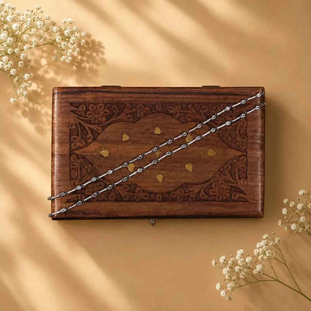 925 silver anklet chain laid across a wooden keepsake box