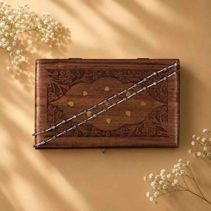 925 silver anklet chain laid across a wooden keepsake box