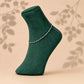 925 silver anklet with linked chain and small charms on dark green sock