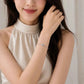 Silver bracelet on wrist with round pavé halo charm and clasp