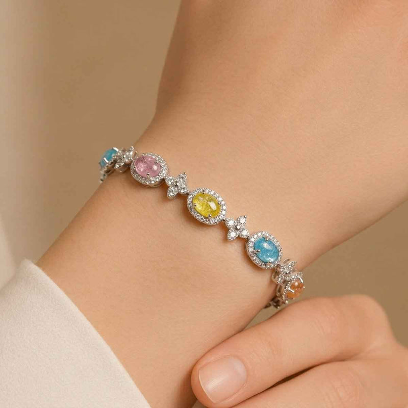 Silver oval halo link bracelet with pastel blue, pink, and yellow stones on wrist