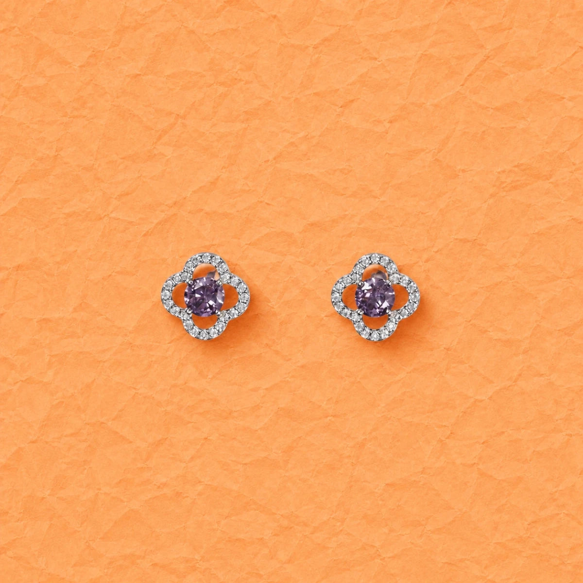 Clover-shaped purple crystal stud earrings with round silver halo detailing