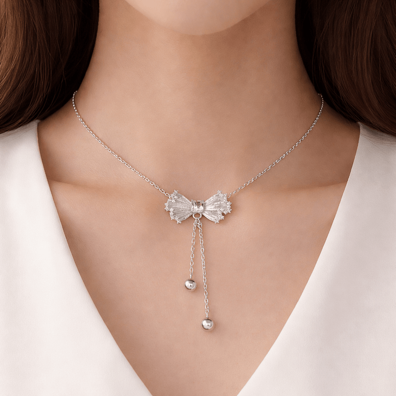 Silver textured bow drop necklace worn with two hanging round bead charms