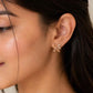 Petal stud earrings worn on ear: pink enamel petals with clear crystal sparkle, small